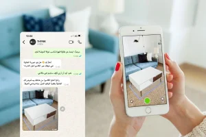امرأة تمسك هاتفاً ذكياً يظهر على شاشته محادثة واتساب مع متجر أثاث، حيث يطلب العميل تجربة طاولة قهوة بتقنية الواقع المعزز. على يمين الصورة، يتم عرض الطاولة الافتراضية عبر الكاميرا داخل غرفة المعيشة، بحيث يمكن رؤية كيف ستبدو الطاولة بجانب الأريكة في المكان الحقيقي. الصورة توضح استخدام الواقع المعزز في التسوق عبر تطبيق المراسلة.