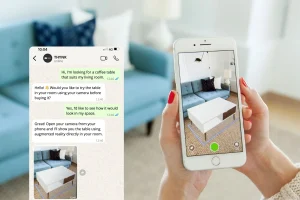 A hand holds a smartphone showing an augmented reality view of a white coffee table in a living room with a blue sofa. Nearby, a chat about the table's fitting.